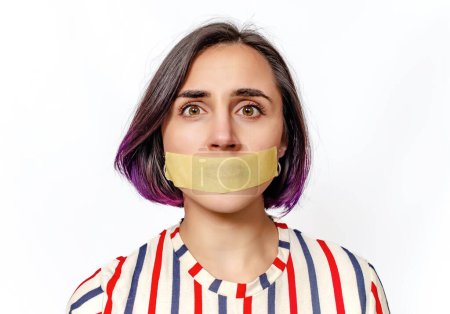Woman's face with taped mouth. Concept of gender inequality and domestic violence. White background