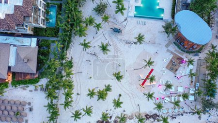 Foto de Complejo hotelero desde altura de dron. Tractor en la limpieza de la playa de arena, preparándose para el día del resort - Imagen libre de derechos