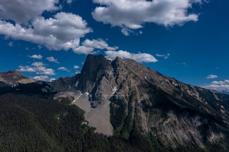 Drone View Berge mit hohen Klippen in Wäldern unter blauem Himmel mit weißen Wolken bedeckt. Kanada