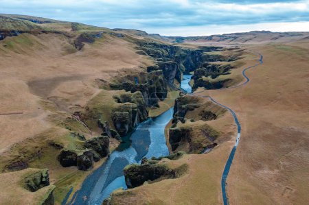 Vertikale Ansicht von oben zwischen Hügeln in Island gewundenen blauen Fluss, Zweig Gebirgsbach. Tourismus