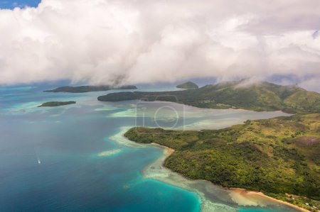 Aguas turquesas bajo las nubes. Montañas en la distancia. Vista del dron de las Islas Fiyi.