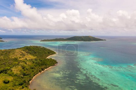 Des eaux océaniques turquoises sous les nuages. Des montagnes au loin. Vue par drone des îles Fidji.