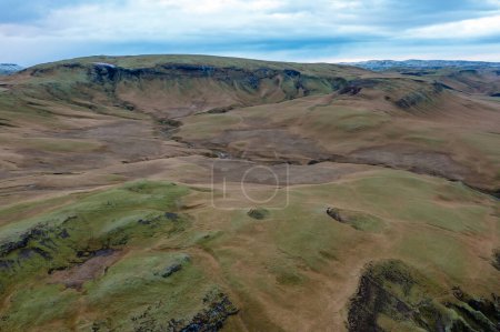 Vulkanische Schlucht mit Hügeln, die mit grünem Gras und Moos bedeckt sind. Drohnenfoto. Ost-Island. Touristische Orte