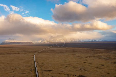 Road through valley of volcanic lava, covered with ash and sand. Sunset clouds. East of Iceland