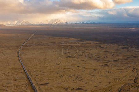 Road through valley of volcanic lava, covered with ash and sand. Sunset clouds. East of Iceland