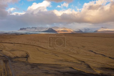 Vue aérienne de la vallée volcanique de lave recouverte de cendres et de sable. Montagnes, nuages au coucher du soleil. Islande orientale