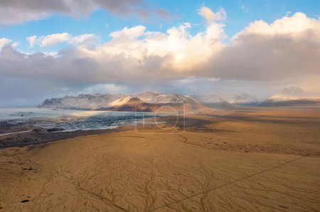 Vue aérienne de la vallée volcanique de lave recouverte de cendres et de sable. Montagnes, nuages au coucher du soleil. Islande orientale