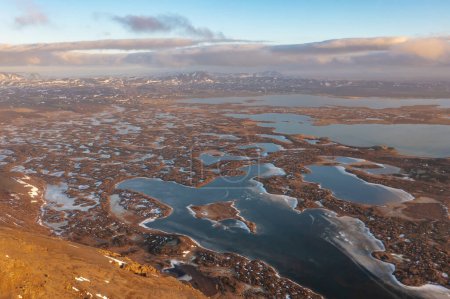 Hiver lacs gelés sur les marécages sur les collines de montagne sous le coucher du soleil nuageux. Islande, région du nord-est
