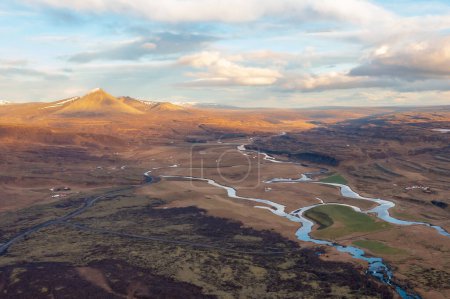 Scenic dron view winding river flowing through meadow in spring. After sunset. Borgarnes Iceland.
