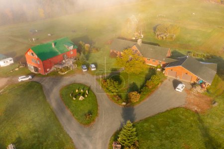 Bauernhof mit Nebengebäuden im Herbstwald unter den Wolken. Drone Drone Ansicht. New Hampshire, USA