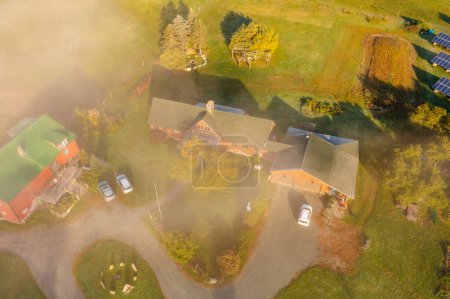 Bauernhof mit Nebengebäuden im Herbstwald unter den Wolken. Drone Drone Ansicht. New Hampshire, USA