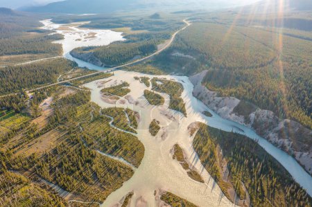 Drone footage of winding river during flood in sunlight. Forest, rocks. Nordegg, Alberta, Canada
