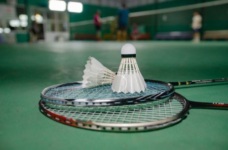 Photo for Badminton rackets and white cream badminton shuttlecocks after playing or after games on green floor in indoor badminton court  soft focus  concept for badminton lovers around the world. - Royalty Free Image