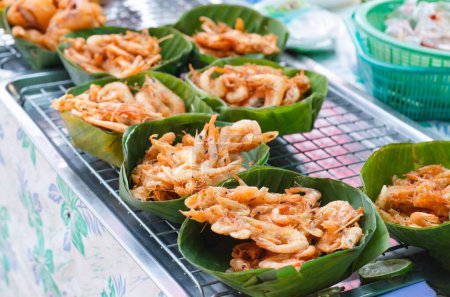 Camarones empanados y otros alimentos fritos en cestas de ratán forradas de hojas de plátano para la venta en un puesto de comida. Deliciosa comida callejera filipina