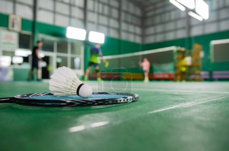 Photo for Badminton rackets and white cream badminton shuttlecocks after playing or after games on green floor in indoor badminton court soft focus concept for badminton lovers around the world. - Royalty Free Image