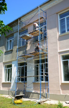 Téléchargez les photos : Les entrepreneurs en construction peignent le mur de façade de maison. Peinture de murs extérieurs. Réparation et rénovation mur avec peinture. - en image libre de droit