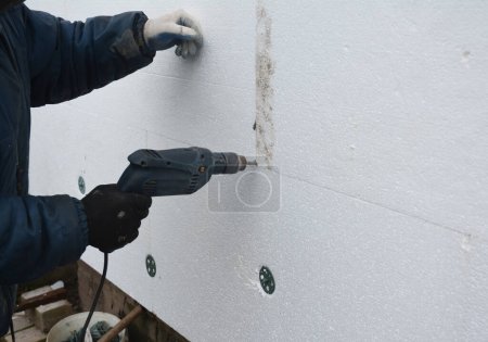 Photo for Builder contractor installing thermal exterior wall insulation. Insulating house walls with rigid foam board. - Royalty Free Image