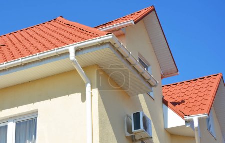 Nahaufnahme auf dem Hausdach aus Metall mit Kunststoff-Regenrinnen-Pipeline, Soffit und Faszien-Platten. Dachgeschosswohnung in Problemvierteln.