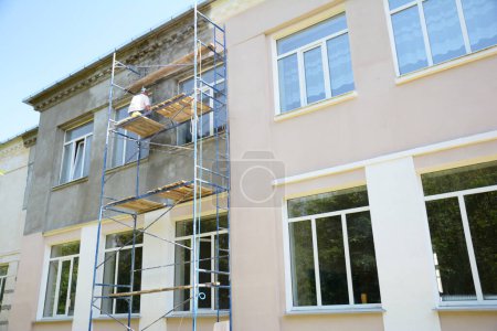 Photo for Builder contractor plastering external walls before painting outside house facade. Prepare for painting house exterior walls. - Royalty Free Image