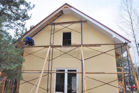Téléchargez les photos : Building contractor installing fascia and soffit board on new painted house. - en image libre de droit