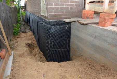 Photo for Basement waterproofing with dimple mat, dimple drain in problem corner area. House  foundation wall insulation with rigid foam board, waterproofing membrane and house foundation construction trench. - Royalty Free Image