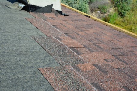 Photo for Installing asphalt roof shingles on the underlayment of the house construction repairing the rooftop in chimney problem area. Roofing construction. - Royalty Free Image