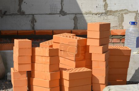 Photo for Pile of clay bricks and bottle with plasticizers for concrete. Plasticizers are the admixtures used to mix in cement to improve their qualities and make them suitable for construction. - Royalty Free Image