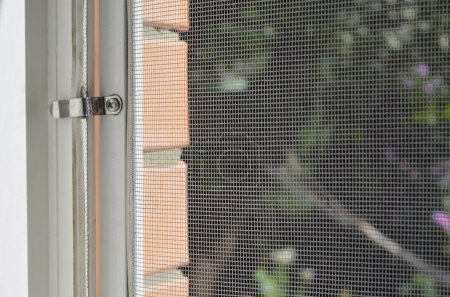 Foto de Mosquitera. Cerca de la pantalla de alambre de mosquito de la casa con los titulares de metal en la ventana para proteger de los insectos. - Imagen libre de derechos