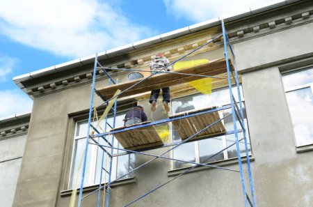 Foto de Contratistas de edificios enluciendo paredes exteriores de la casa. Renovación de casas con paredes de yeso y pintura. - Imagen libre de derechos