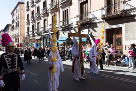 Foto de Madrid, España; 2 de abril de 2023: Procesión de la Semana Santa del Domingo de Ramos, coloquialmente llamada "el borriquito" .Miembros vestidos de blanco con capuchas, togas y guardias en traje ceremonial - Imagen libre de derechos