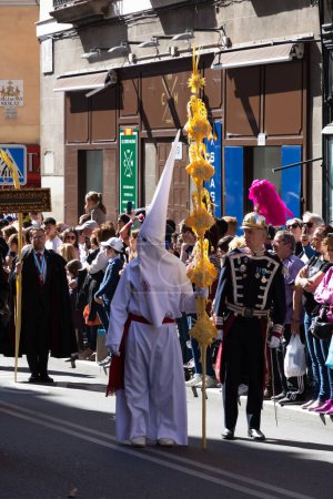 Foto de Madrid, España; 2 de abril de 2023: Procesión de la Semana Santa del Domingo de Ramos, coloquialmente llamada "el borriquito" .Miembros vestidos de blanco con capuchas, togas y guardias en traje ceremonial - Imagen libre de derechos