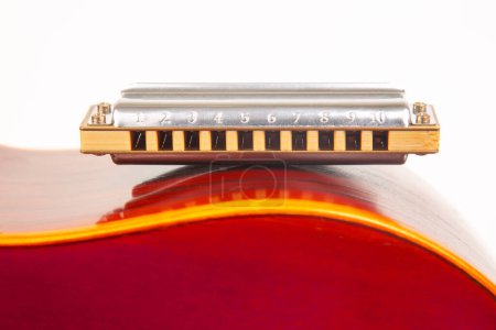 Photo for The harmonica rests on the body of a classical guitar. Classical musical wind instrument. - Royalty Free Image