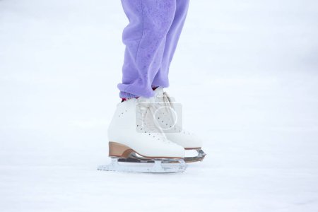 Beine eines Schlittschuhläufers auf einer Eisbahn. Hobbys und Wintersport
