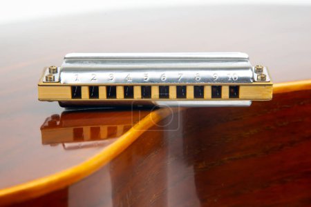 Photo for The harmonica rests on the body of a classical guitar. Classical musical wind instrument. - Royalty Free Image