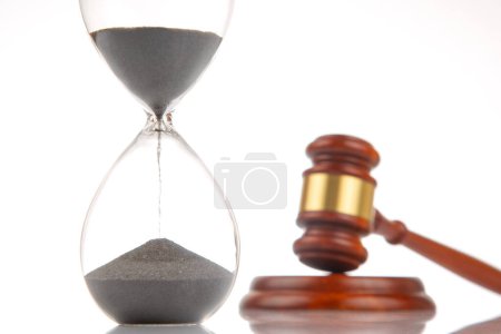 Justizgabel auf dem Hintergrund einer Sanduhr. Zeitpunkt des Urteils und Dauer der Gerichtsentscheidung