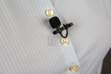 Foto de Micrófono lavalier para grabación de voz en la camisa. tecnología de dispositivo de audio. micrófono pequeño con cable - Imagen libre de derechos