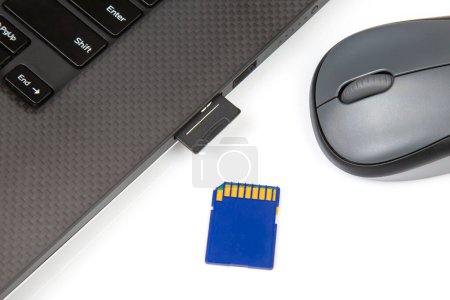 sd memory card for recording electronic data near a laptop on a white background. electronic industry and information items