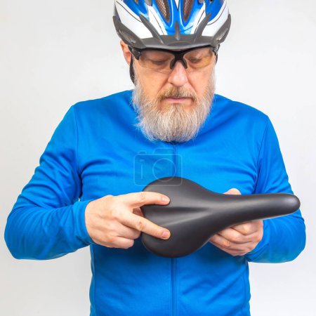 male cyclist checks the softness of his bicycle saddle. sports and transport equipment