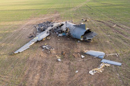 En esta foto, se puede ver un avión AN-26 tumbado en un campo en Ucrania después de un accidente. El avión parece haber sufrido daños significativos, con partes dispersas alrededor de los restos. El