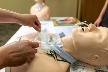 A Person Putting Oxygen On A Mannequin Persons Hand Holding A Tube. High quality photo A healthcare professional meticulously attends to a life-sized mannequin resembling a newborn. The scene unfolds