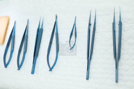 Stainless Steel Surgical Instruments on Draped Table. High quality photo a close-up of a set of stainless steel surgical instruments on a sterile, draped table. The instruments are arranged neatly and