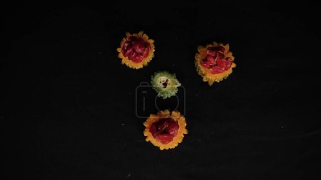Foto de Tres rebanadas de calabaza amarilla amarilla con semillas rojas en rebanadas, una rebanada de calabaza amarga verde aislada sobre fondo negro - Imagen libre de derechos