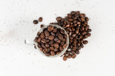 Foto de Granos de café derramándose sobre fondo blanco y taza de café llena de granos de café - Imagen libre de derechos