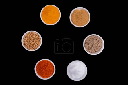 Photo for Six Round Bowls In Round Style Filled With Spices. Isolated On Black Background. Spices Like, Mustard Seeds, Coriander Seeds, Cumin Seeds, Red Chili Powder, Turmeric Powder And Salt. Copy Space - Royalty Free Image