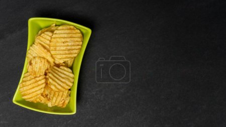 Photo for Home Made Potato Wafer Or Potato Chips In Green Bowl, Isolated On Black Paper Background With Copyspace - Royalty Free Image