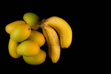Téléchargez les photos : Mangues avec bananes isolées sur fond noir, espace de copie - en image libre de droit