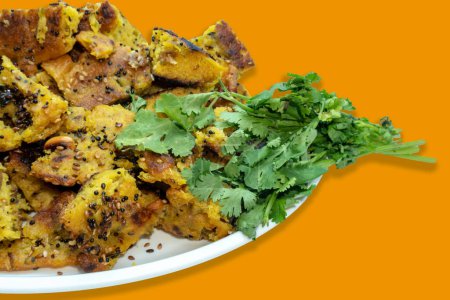 Téléchargez les photos : Gâteau aux légumes Gujarati Handvo / Handwa très gros plan, Petits morceaux de Handwa avec feuilles de coriandre isolées sur fond jaune - en image libre de droit