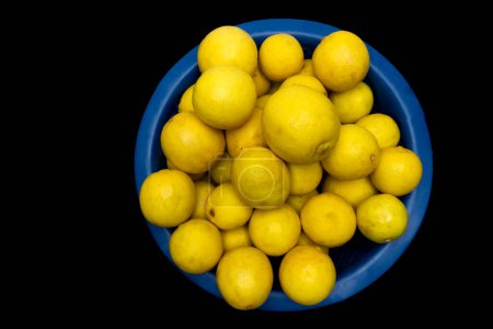Téléchargez les photos : Tas de citron dans un bol en plastique isolé sur fond noir - en image libre de droit