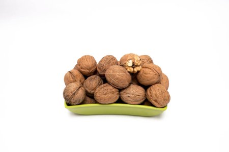 Fresh, Whole Walnuts in a Vibrant Green Bowl, This image features a collection of fresh, whole walnuts neatly placed in a vibrant green bowl. One walnut is cracked open, revealing the seed inside