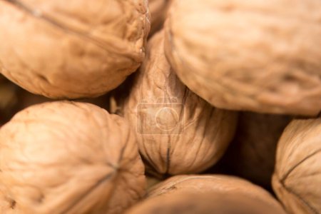 Foto de Golden Delight: A Close-Up of Textured Walnuts, Esta imagen presenta un primer plano de un grupo de nueces, sus intrincadas texturas bellamente resaltadas. Cada nuez, encerrada en su caparazón - Imagen libre de derechos